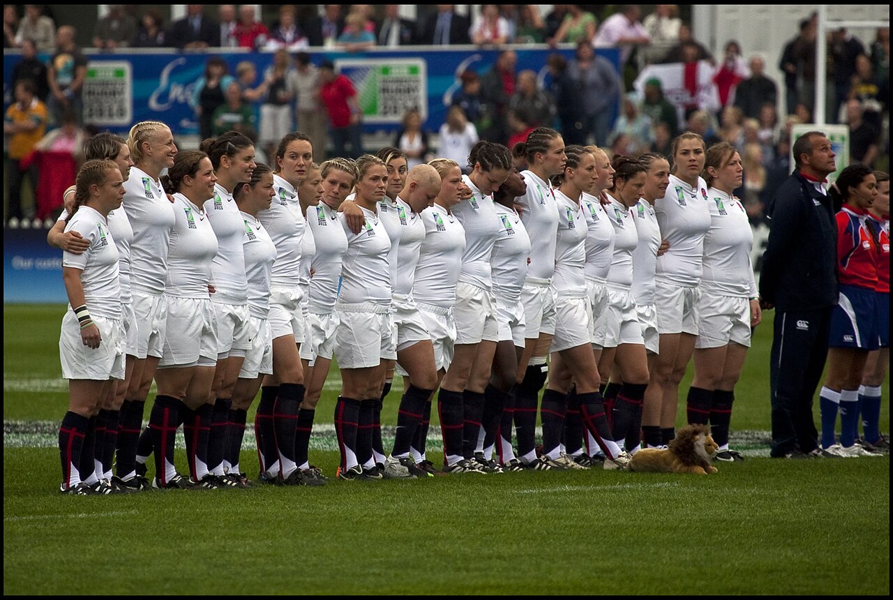 The England women's rugby team standing in a line on the field.