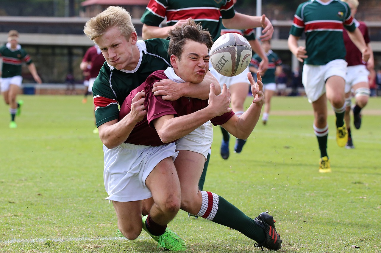 Rugby players tackling each other on a grass field during a match.