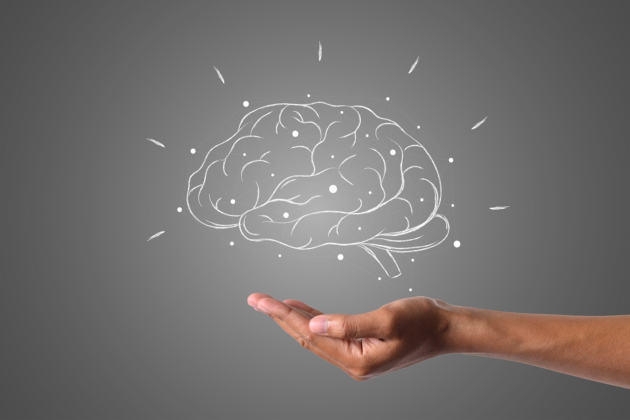 A hand holding a glowing, sketched illustration of a human brain.