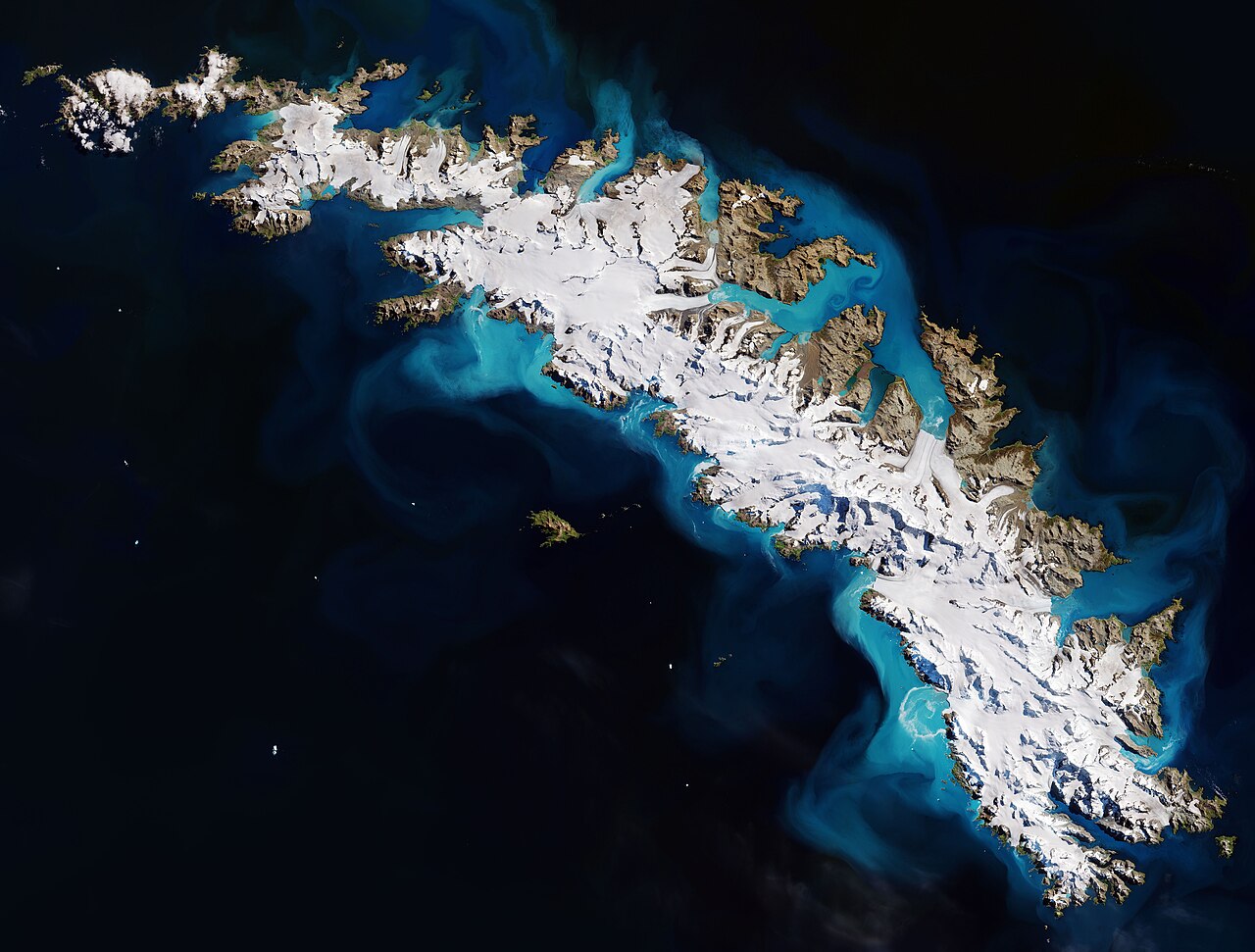 A satellite image from Sentinel-3 of South Georgia island showing snow-covered mountains surrounded by deep blue ocean water and bright turquoise phytoplankton blooms.