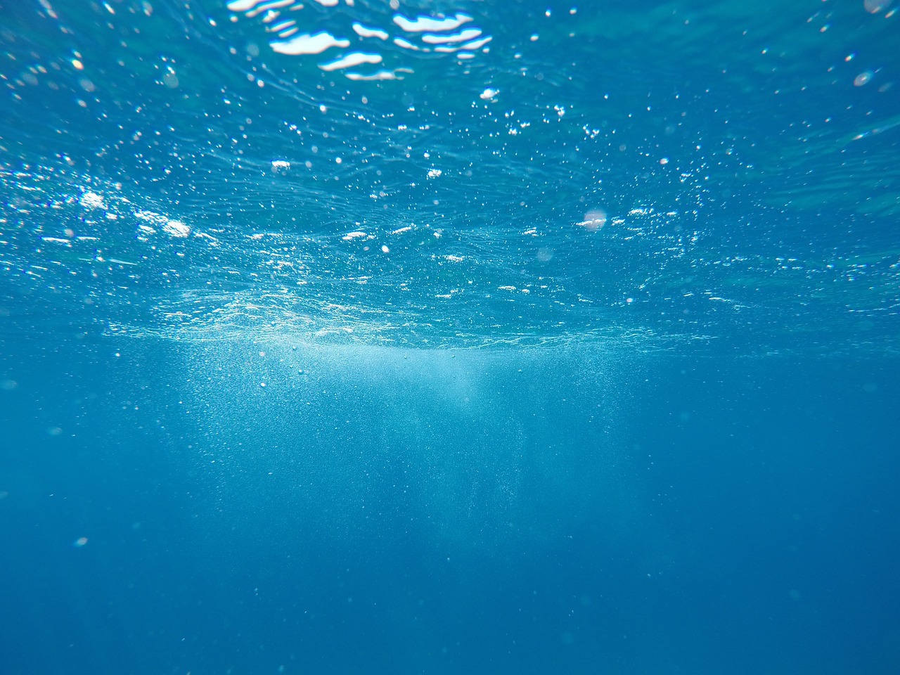 An underwater view of the ocean surface with sunlight filtering through the water.
