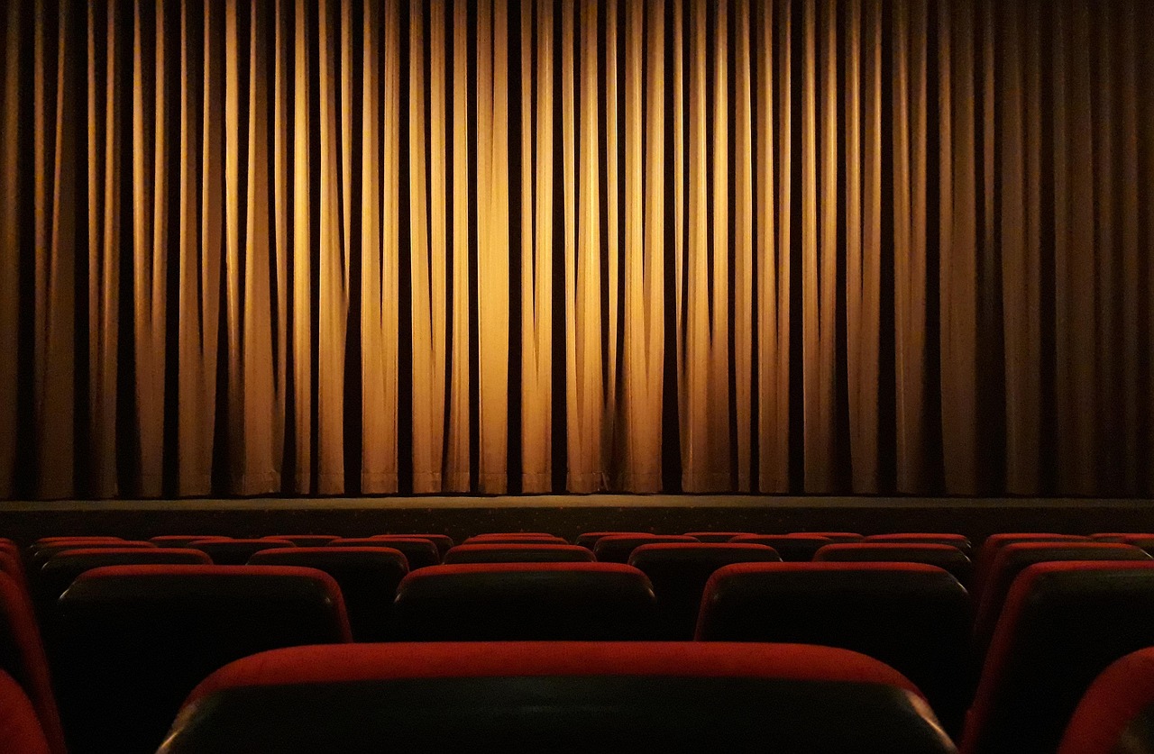 A view from the audience looking at a closed stage curtain in a theater.