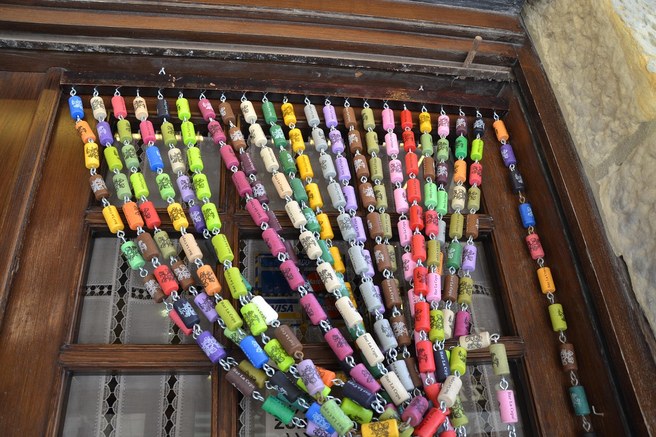 A beaded curtain made from colorful painted wine corks hanging in front of a wooden door.