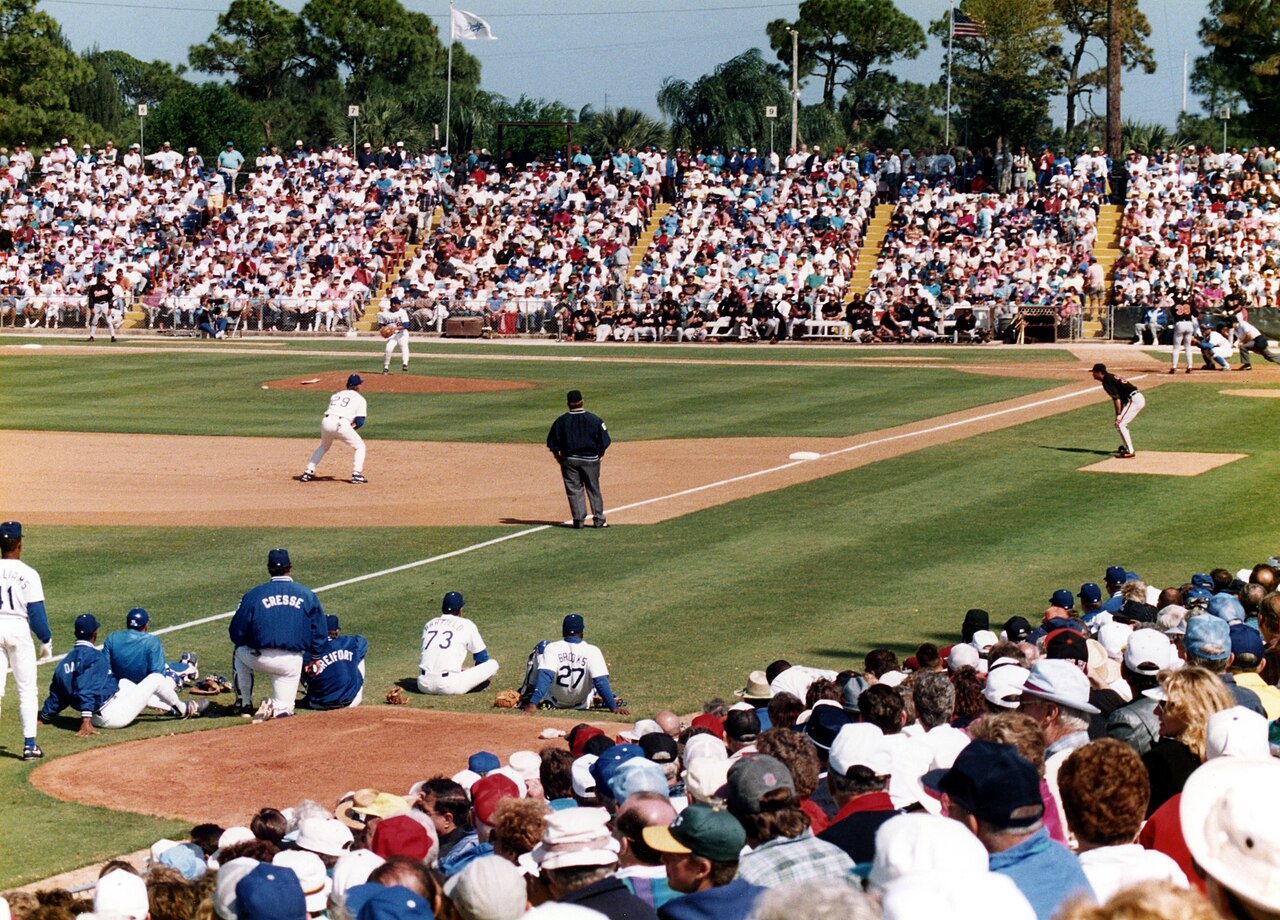 A baseball game in progress at a stadium with a full crowd in the stands and players on the field.